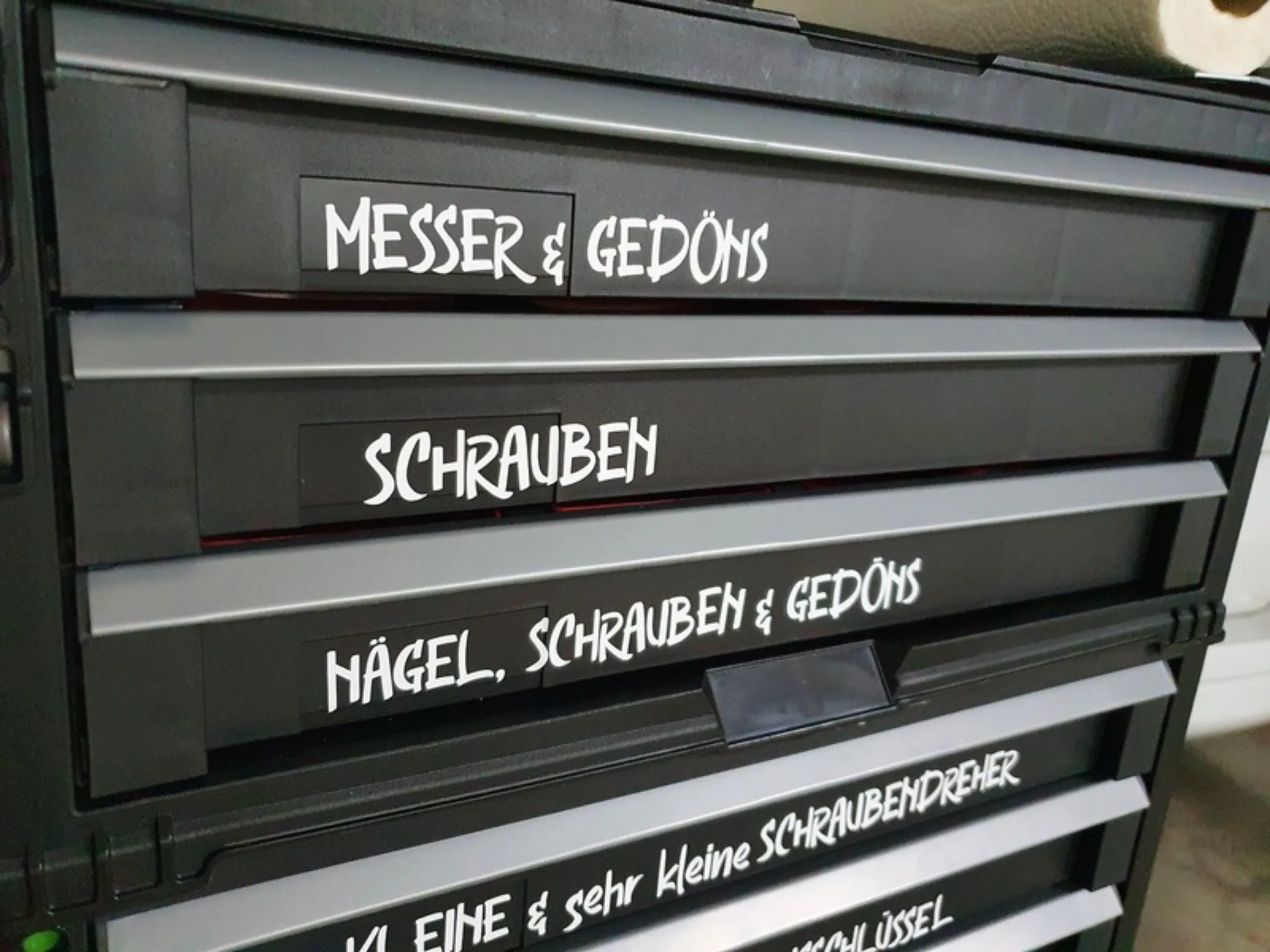 Nahaufnahme der beschrifteten Werkzeug-Schubladen: Messer und Gedöns, Schrauben, Nägel Schrauben und Gedöns