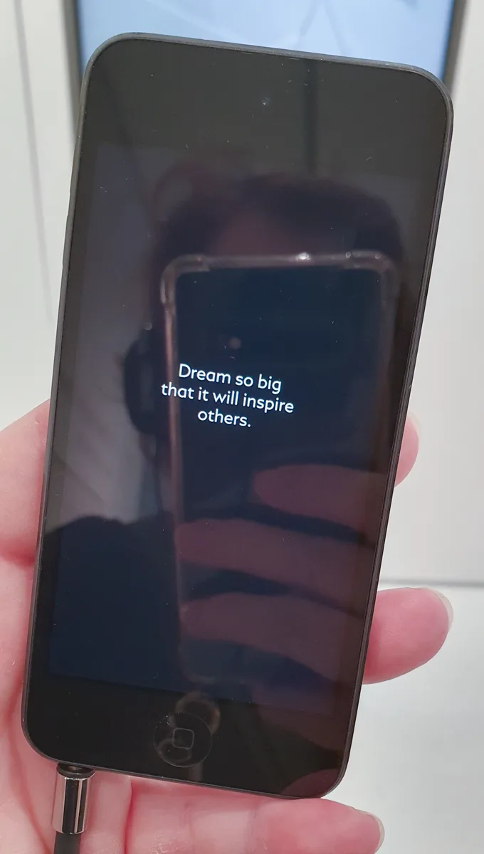 Smartphone-Bildschirm mit dem Zitat Dream so big that it will inspire others in weißer Schrift vor unscharfem hellblauem Hintergrund.