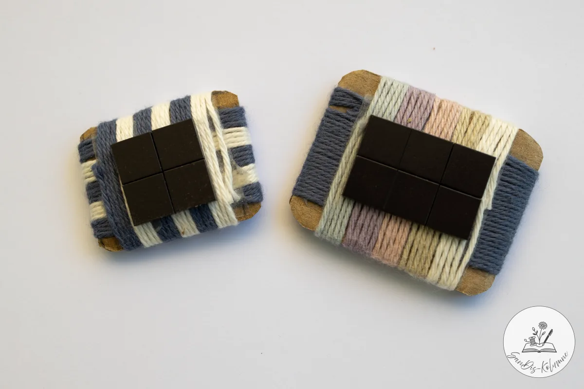 Zwei Webstücke zeigen ihre Rückseite mit aufgeklebten dunklen Magnetplättchen, links vier, rechts sechs.