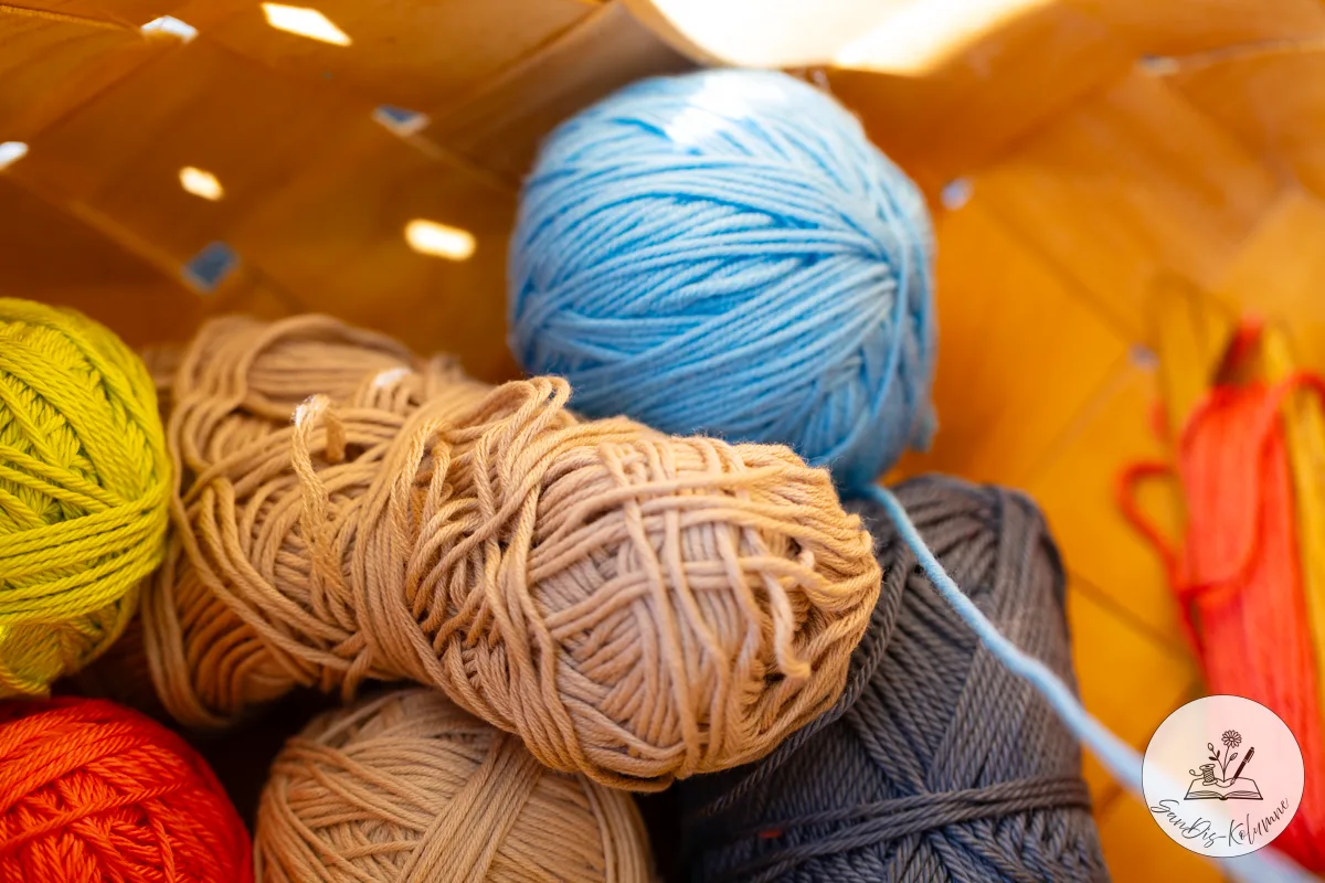Bunte Wollknäuel in einem Korb: Hellblau, Beige, Gelbgrün, Rot und Grau